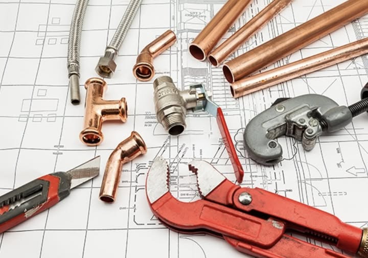 Plumber repairing burst pipe under sink in NYC apartment